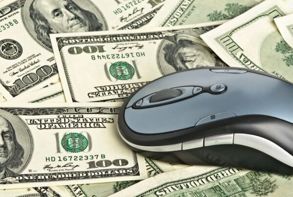 Close up with computer mouse on money to signify wire fraud.